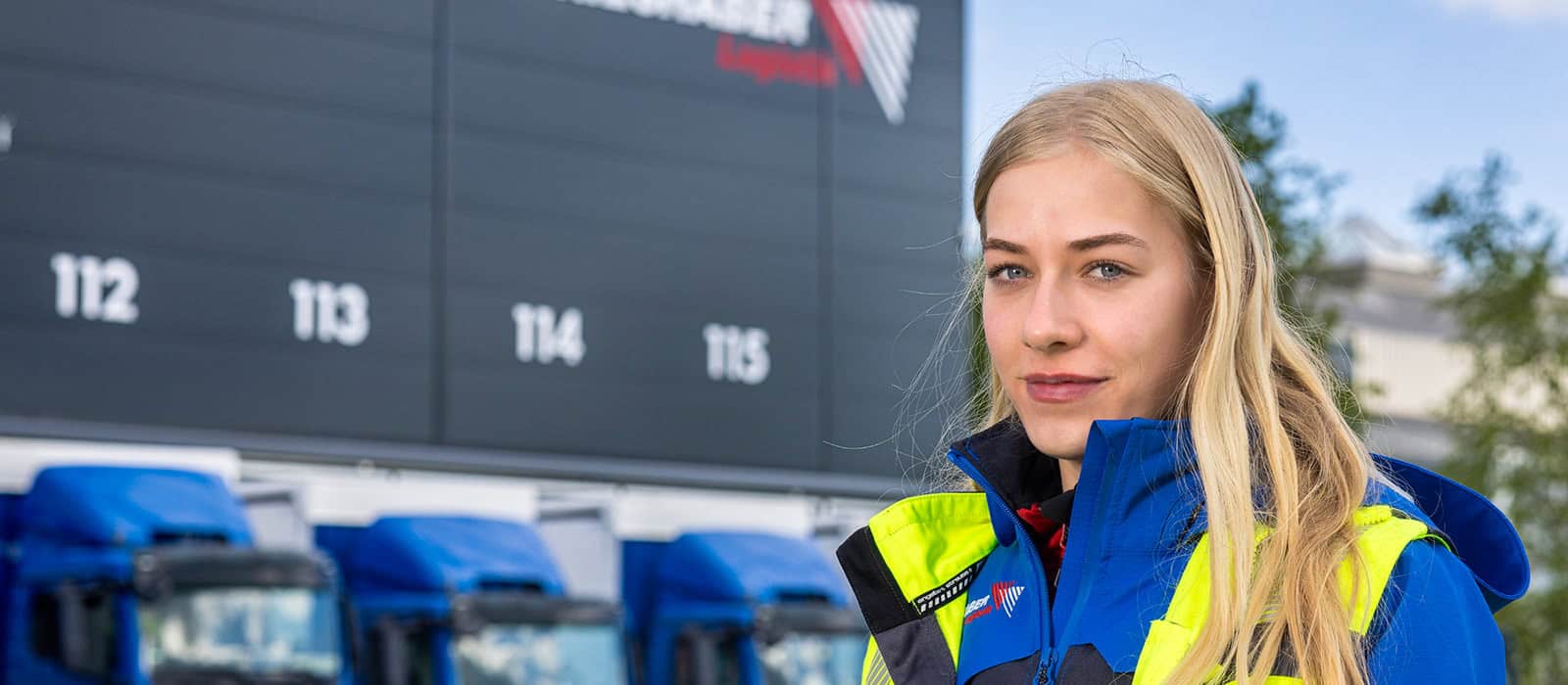 Lkw Fahrerin steht vor Fahrzeugflotte in Weingarten